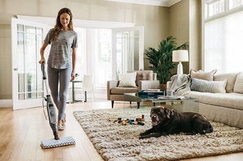Woman mops the laminate floor with the Shark Genius Mop.